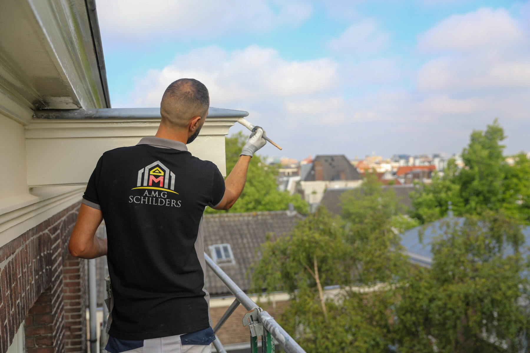 Schilder op een balkon boven de Amsterdamse daken